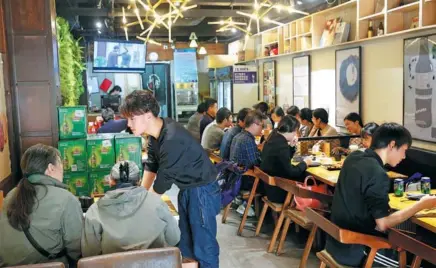  ?? WANG ZHUANGFEI / CHINA DAILY ?? Customers eat lunch at the Lancet Barbecue, which gives discounts to people who have had papers published in academic journals.