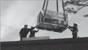  ?? Photo by Joseph B. Nadeau ?? Above: Workers with Kafin Oil & HVAC work to bring in a new HVAC unit for the Woonsocket Senior Citizen Center on Thursday.