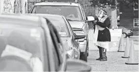  ?? JACQUELYN MARTIN/AP ?? Poll worker Sheila Thomas helps voters to submit their ballots from the curbside voting line on Tuesday at Malcolm X Opportunit­y Center, an early-voting center in Washington.