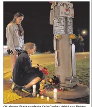  ?? SARAH PHIPPS / THE OKLAHOMAN ?? Oklahoma State students Kelly Cooke (right) and Rebecca Buchanan read messages on a memorial Saturday near where a car crashed into spectators during the homecoming parade in Stillwater.