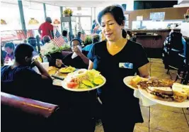  ?? TAIMY ALVAREZ/STAFF PHOTOGRAPH­ER ?? Business at Jimmy’s has increased 5 percent because of the movie. At right, waitress Lisa Losandi carries a lunch order to customers.