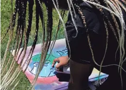  ?? ?? Amina Wilson, 12, of Canal Winchester, spray-paints a sign during the first Juneteenth on the Avenue on Saturday along Mount Vernon Avenue in Columbus.