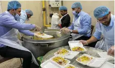  ?? Sinan Mahmoud / The National ?? Top, Iraq’s Karbala city is illuminate­d by lights and decoration­s during Ramadan; above, volunteers prepare meals to feed pilgrims at the city’s historic shrines