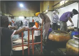  ?? (File Photo/AP/Manish Swarup) ?? Sikh volunteers load prepared food May 10 onto a trolley to be taken out from the kitchen hall of the Bangla Sahib Gurdwara in New Delhi, India.