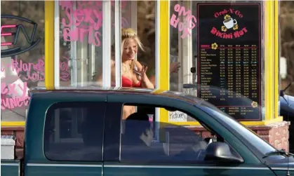  ?? Photograph: Ted S Warren/AP ?? A barista at a Grab-N-Go Bikini Hut espresso stand holds money as she waves to a customer, just outside the city limits of Everett, Washington.