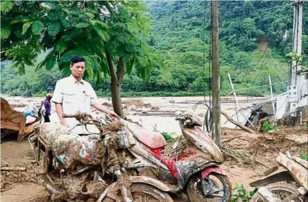  ?? — AFP ?? Muddled by floods: ( Top) A man looking at motorbikes damaged by flash floods in Yen Bai province. (Right) A general view showing debris in a village damaged by flash floods in Yen Bai.