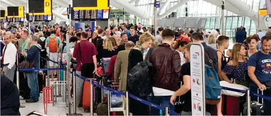  ??  ?? Grounded: Passengers are forced to wait in line to manually check in at BA departure desks at Heathrow yesterday