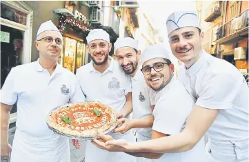  ??  ?? Neapolitan pizza makers pose with a pizza celebratin­g the Unesco decision to make the art of Neapolitan ‘Pizzaiuolo’ an ‘intangible heritage’ outside the Pizzeria Brandi in Naples. — AFP photo