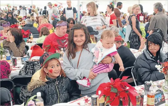  ?? Photos: DONSCOTT/FAIRFAX NZ ?? Festive: Maiden Milton, 8, left, and Anzonette, 11, enjoy some festive cheer with their nine-month-old brother, TeAroha, at his first Christmas lunch at the Christchur­ch City Mission. Food for all: Lunches are prepared for the mission
Christmas lunch...