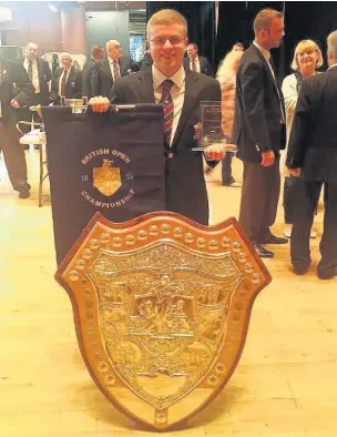  ??  ?? Cory Band horn player Ross Dunne with British Open Championsh­ip Shield