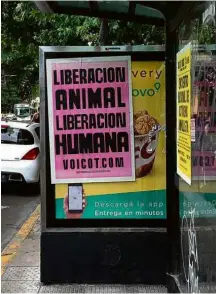  ?? Sylvia Colombo/Folhapress ?? Cartaz de ativistas veganos colado em cima de propaganda de fast-food de frango em Buenos Aires