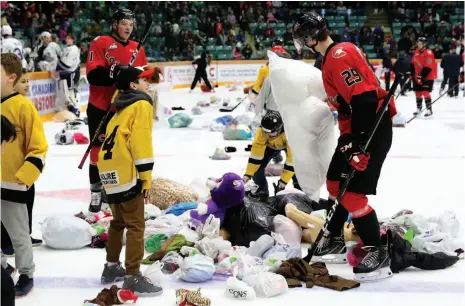  ?? CITIZEN PHOTO BY JAMES DOYLE ?? Prince George Cougars forwards Vladislav Mikhalchuk, right, and Josh Maser help collect teddy bears and other items thrown onto CN Centre ice by fans on Sunday afternoon. In the Cougars’ annual Teddy Bear Toss game, Mikhalchuk scored the goal that brought stuffed animals and warm winter clothing out of seats occupied by 3,614 spectators. The Cougars beat the Victoria Royals 5-3.