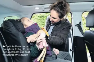  ??  ?? Debbie Hale helps daughter Ruby, 11, into her specialist car seat provided by Newlife
