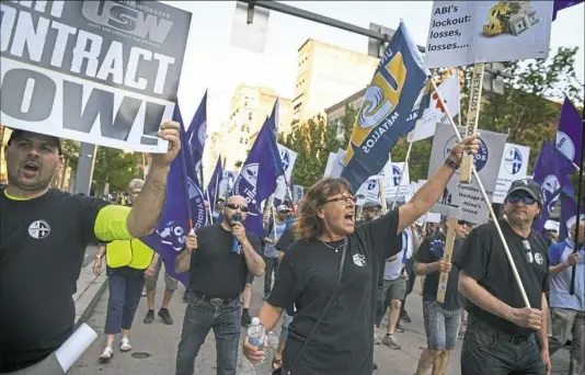  ?? Steve Mellon/Post-Gazette ?? Martine Gauthier, center, joined about 100 other locked-out workers from the ABI aluminum smelter in Becancour, Quebec, marching through Downtown Pittsburgh on Wednesday to protest the company’s actions. ABI, a joint venture between majority owner...