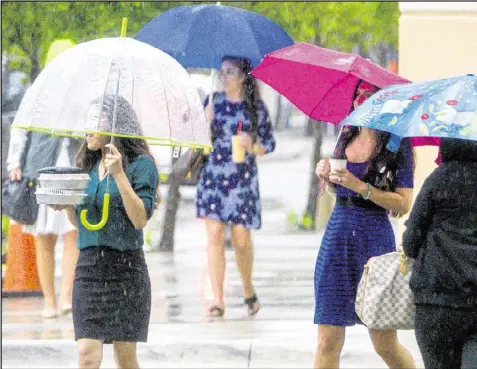  ?? LANNIS WATERS / THE PALM BEACH POST ?? Pedestrian­s try to keep dry while crossing Banyan Boulevard in downtown West Palm Beach on Tuesday. Rain is expected to continue in Palm Beach County for the next several days.