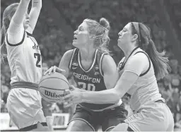  ?? RON JOHNSON/AP ?? Creighton guard Morgan Maly (30) drives to the basket as Iowa guard McKenna Warnock (14) reaches for the ball during the second round of the women’s NCAA Tournament on Sunday in Iowa City, Iowa.