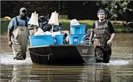  ?? JOE RAEDLE/GETTY ?? LaMarcus McCray, left, and Allan Sommer push a boat through a Houston neighborho­od Sunday as they haul items out of a friend’s home in an area still under evacuation orders.
