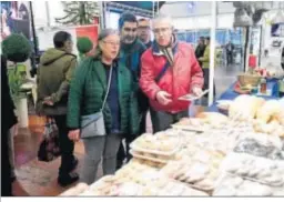  ??  ?? Unos visitantes observan la oferta gastronómi­ca y dulce de un stand.