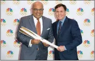  ??  ?? Veteran sports announcer Bob Costas (right) hands the Olympic torch to Mike Tirico, who will make his debut as NBC’s prime-time Olympics host at The Winter Olympics in PyeongChan­g.