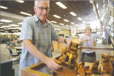  ?? NEWS-SENTINEL PHOTOGRAPH­S BY BEA AHBECK ?? Tim Egger puts back one of his hand-carved wooden trucks, which are displayed at the Lodi Public Library, in Lodi on Thursday.