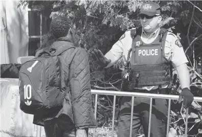  ?? PAUL CHIASSON / THE CANADIAN PRESS FILES ?? An asylum seeker, claiming to be from Eritrea, is questioned by an RCMP officer as he crosses the border into Canada from the United States last August near Champlain, N.Y.