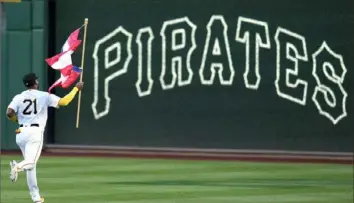  ?? Gene J. Puskar/Associated Press ?? Pirates right fielder Joshua Palacios carries a Puerto Rican flag for Roberto Clemente Day to his position in right field, before the team’s game Sept. 15 against the Yankees at PNC Park. “Obviously we all celebrate the legacy and life of Roberto Clemente, what he meant to the Pirates in particular,” Pirates president Travis Williams said earlier this month. “I think we’d all love to see his number retired across the league. We certainly celebrate on Clemente Day. We’ve retired it ourselves, but we also celebrate on Clemente Day by wearing 21.