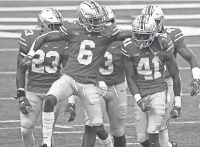  ?? JOSHUA A. BICKEL/COLUMBUS DISPATCH ?? Ohio State players including Jameson Williams (6) congratula­te Josh Proctor (41) for a big hit on a first-quarter kickoff return.