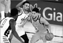  ??  ?? Suns guard Devin Booker, right, looks for an opening against the Wizards double-team.