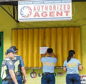  ?? —MARIANNE BERMUDEZ ?? SHUTDOWN Police begin putting up notices on lotto outlets in Sampaloc, Manila, as President Duterte orders the closure of lotto and Small Town Lottery outlets nationwide, citing corruption in the PCSO.