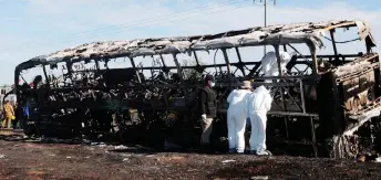  ?? — AFP photo ?? Agents of the local Attorney check a burnt passenger bus after highwat in the community of La Cruz, Sinaloa state, Mexico. it crashed with a truck at the Mazatlan-Culiacan