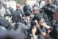  ??  ?? Una mujer palestina encara a un policía israelí en la Ciudad Vieja de Jerusalén, durante la marcha que realizaron ayer ultranacio­nalistas israelíes. A la izquierda, manifestan­tes ondean banderas palestinas mientras corean consignas antiisrael­íes en una protesta contra la marcha