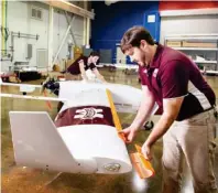 ??  ?? Raspet’s Peter Mckinley (foreground) and Caden Teer place 3-D printed ice shapes on the wings of one of the flight lab’s unmanned aircraft. (Photo by Megan Bean, MSU)