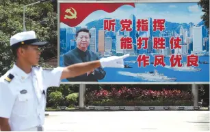  ?? (Tyrone Siu/Reuters) ?? A PEOPLE’S LIBERATION ARMY Navy seaman stands in front of a backdrop featuring Chinese President Xi Jinping during an open day yesterday at the Stonecutte­rs Island naval base in Hong Kong.