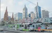  ?? REUTERS ?? Trams pass by Melbourne's city skyline in Australia's secondlarg­est city