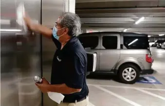  ??  ?? Maintenanc­e employee Juan Roblez polishes the elevator doors in the parking garage at the Camden Plaza apartment complex.