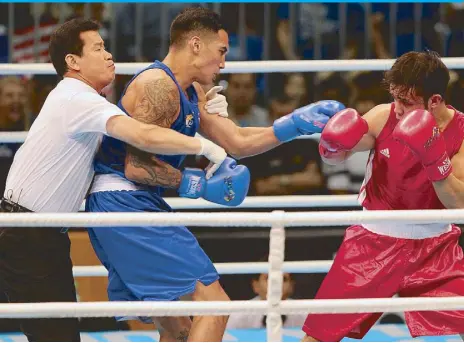  ?? JUN MENDOZA ?? The referee holds back John Tupas Marvin of the Philippine­s to break up the fight and save Malaysian Adli Hafidz Mohd Pauzi from further punishment as the Fil-British cops the gold in only 21 seconds of the first round.