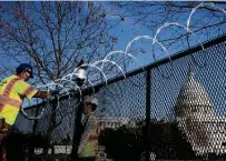  ?? Chip Somodevill­a / Getty Images ?? Workers put concertina razor wire along the top of the 8-foot “nonscalabl­e” fence that now surrounds the Capitol the day after the House voted to impeach President Donald Trump.
