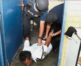  ??  ?? No escape: The suspect being restrained by the policemen.