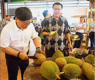  ??  ?? Offbeat meeting: Liow watching Zhou opening a Musang King durian during the visit to Bentong.