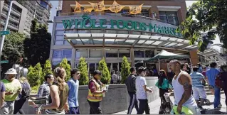  ?? ELAINE THOMPSON / ASSOCIATED PRESS ?? People walk past a Whole Foods Market just down the street from Amazon’s headquarte­rs in Seattle. Even after acquiring Whole Foods, Amazon will have less than 3 percent of the U.S. market share in groceries, Kantar Retail says. Walmart is the leader,...