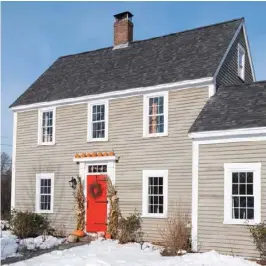  ??  ?? Against an unseasonab­ly early snowfall, a bold red door and stark white window trim enliven the weathered clapboard siding of the McMahons’ New England Colonial-style home.