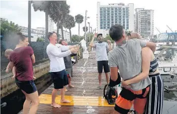  ?? MIKE STOCKER/SOUTH FLORIDA SUN SENTINEL PHOTOS ?? Charley McColough opens a bottle of Champagne as he and other friends welcome Eric Bihl and Kennon Jones home on Thursday as they arrive at the Hall of Fame Marina in Fort Lauderdale after successful­ly circumnavi­gating the globe.