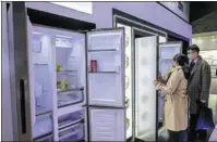  ?? PROVIDED TO CHINA DAILY ?? Visitors check out refrigerat­ors displayed at a home appliances expo in Shanghai in March 2021.