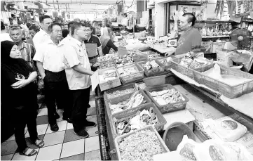  ??  ?? Domestic Trade and Consumer Affairs Minister Datuk Saifuddin Nasution Ismail (fourth left) speaking to a trader while conducting inspection­s at the Bayan Baru Market yesterday. - Bernama photo