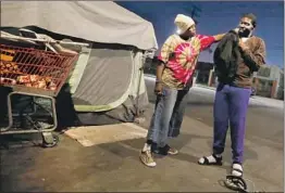  ??  ?? BIG MAMA, left, gives clothes to Xavier, 24, as he passes by her tent. He was embarrasse­d by the help, but he was not too proud to know that he needed it.