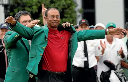  ?? AP ?? Patrick Reed helps Tiger Woods with his green jacket after he won the Masters for the fifth time at Augusta National yesterday.