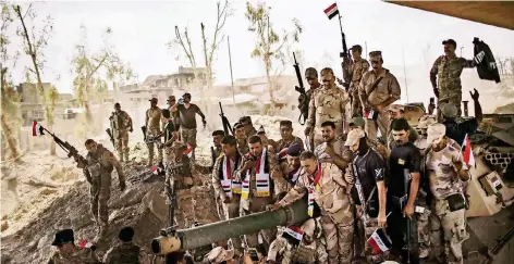 ?? FOTO: DPA ?? Irakische Soldaten feiern in der Altstadt von Mossul ihren Sieg. Einer präsentier­t eine erbeutete Flagge des IS (r.).