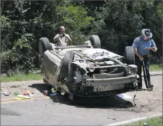  ?? The Sentinel-Record/Mara Kuhn ?? FLIPPED: Garland County Coroner Stuart Smedley, left, and Arkansas State Police Cpl. James Avant work the scene of a fatal wreck on Cedarglade Road just west of its intersecti­on with Turkey Trot Lane around noon Saturday.