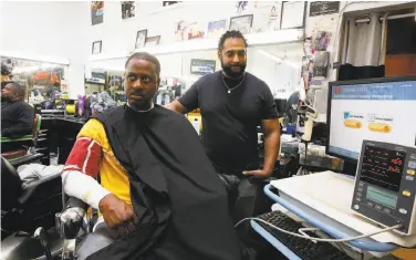 ?? Damian Dovarganes / Associated Press ?? Eric Muhammad, owner of A New You Barbershop, measures the blood pressure of customer Marc Sims.