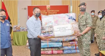  ??  ?? Mohd Halim (right) handing over the assistance to Yakubah while Syed Mohd (left) looks on.